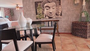 Ein Essbereich mit einem Glastisch, schwarzen Stühlen und Wandkunst mit Buddha-Motiv.