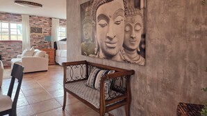 Ein Wohnzimmer mit großem Buddha-Gemälde, einer Couch, einer Holzbank und einer Ziegelwand.