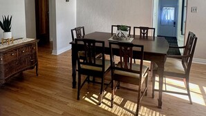 A dining room with a wooden table and chairs, a chandelier, and a potted plant. - Modern Tree-Street Retreat/Walkable Location (Casper)