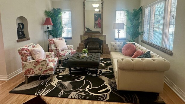 A living room with a fireplace, floral armchairs, a sofa, and a patterned rug. - Modern Tree-Street Retreat/Walkable Location (Casper)