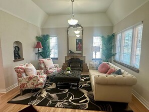 A living room with a fireplace, floral armchairs, a sofa, and a patterned rug. - Modern Tree-Street Retreat/Walkable Location (Casper)