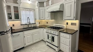 A kitchen with white cabinets, a stove, and a sink. - Modern Tree-Street Retreat/Walkable Location (Casper)