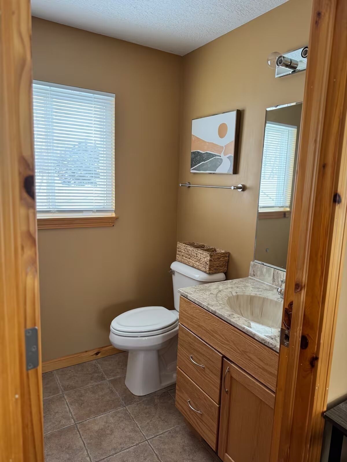 A compact bathroom with a toilet, vanity, and a window.