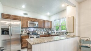 A modern kitchen with stainless steel appliances, wooden cabinets, and a granite countertop island. - Carson Flats Apt #4 | 1BR • Near BOK• OSU Med•Dtwn (Tulsa)