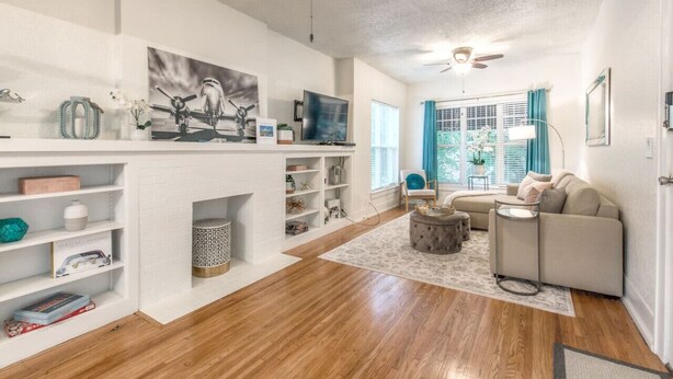 A modern living room with a fireplace, a sofa, a coffee table, and a TV. - Carson Flats Apt #4 | 1BR • Near BOK• OSU Med•Dtwn (Tulsa)