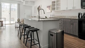 Une cuisine moderne dotée d’un îlot central, de tabourets de bar, d’un évier en acier inoxydable et d’armoires en bois foncé.