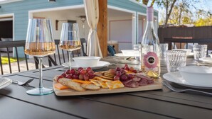 Une table dressée pour un repas, avec une planche de charcuterie, des verres et une bouteille de vin rosé.