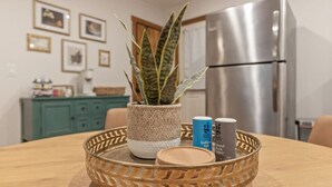 A kitchen with a stainless steel refrigerator, a woven basket on a wooden table, and a potted plant. - Rustic Charm Owasso Retreat | 2BR • Big Backyard (Owasso)