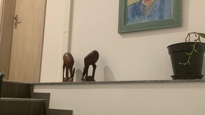 A staircase with dark tiles, a door, a framed painting, and two small sculptures. - Le Bastion, l'appartement au pied de la Citadelle (Bitche)