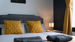 A neatly made bed with a checkered bedspread, two pillows, and rolled towels. - Open Mind Property - 7 Beds and Free Parking (Portsmouth)