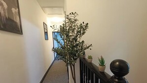 A hallway with a staircase, a potted plant, and a small table with a plant on it. - Open Mind Property - 7 Beds and Free Parking (Portsmouth)
