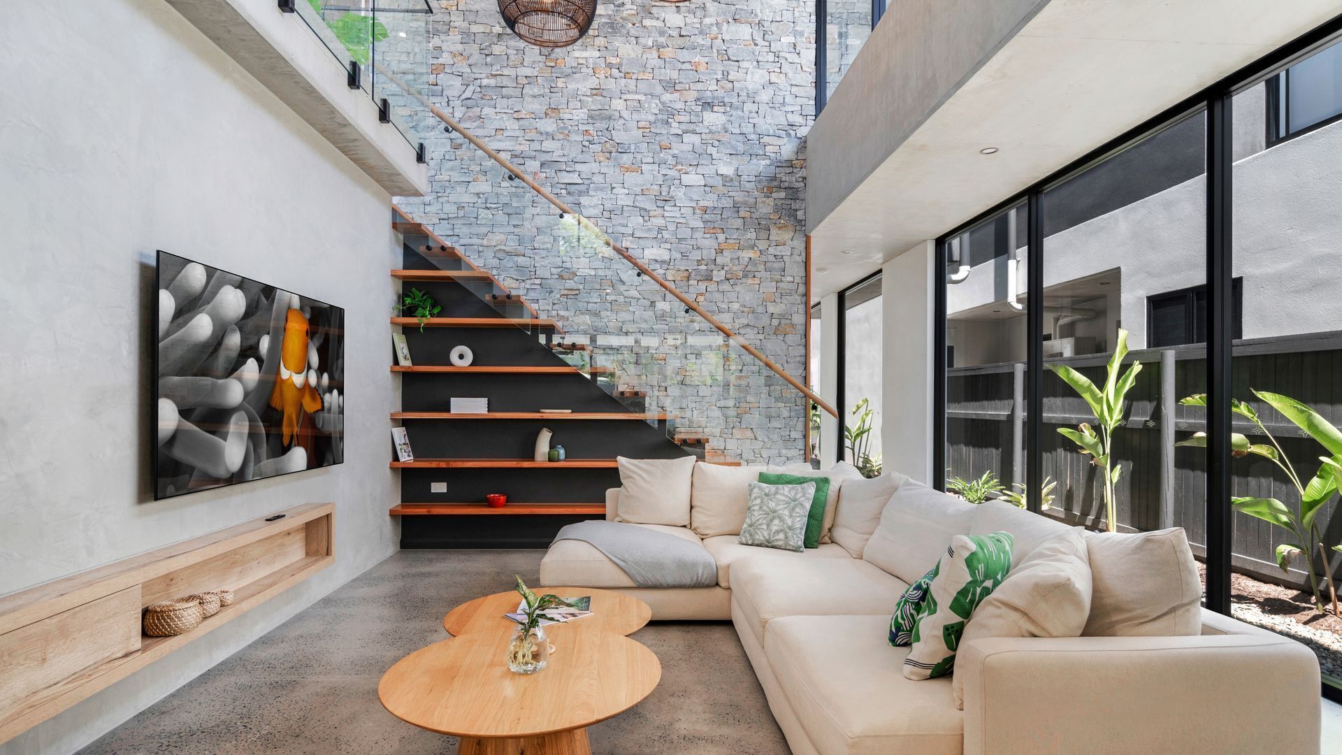 A modern living room with a stone wall, a staircase, a sofa, and a coffee table.