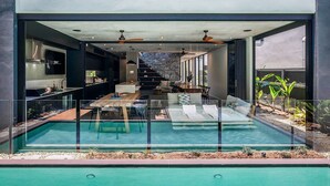 A modern house with a glass-enclosed swimming pool, a kitchen, and a dining area.