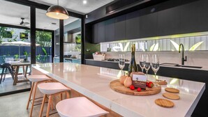 A modern kitchen with a large island, bar stools, a wine bottle, glasses, and a chocolate bar.