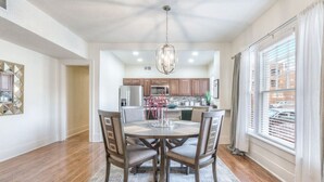 A dining area with a round table, chairs, and a chandelier. - Carson Flats Apt #2 | 1BR • Near BOK• OSU Med•Dtwn (Tulsa)