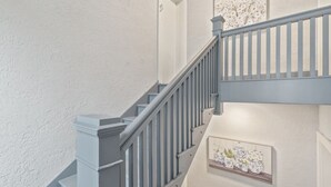 A staircase with a white wall and a framed picture of potted plants. - Carson Flats Apt #2 | 1BR • Near BOK• OSU Med•Dtwn (Tulsa)