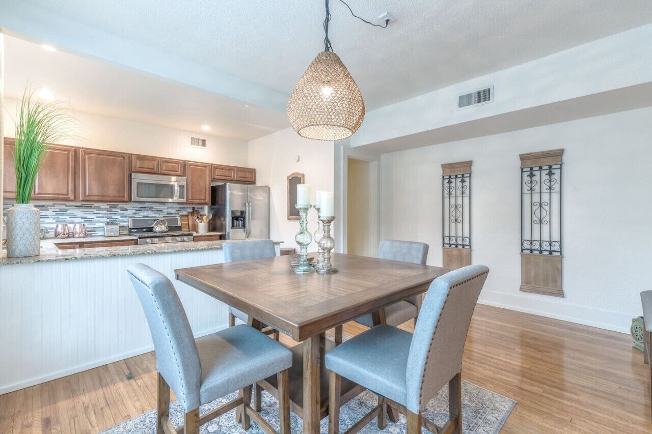 A modern kitchen with wooden cabinets, a central island, and a dining area with a wooden table and chairs.