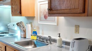 Una cocina con armarios de madera, encimera de granito, pileta, estufa y tostadora.