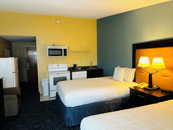Habitación de hotel con dos camas, microondas, estufa, lavabo y teléfono.