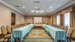 A conference room with a long table, chairs, a projector screen, and patterned carpet. - Regency Inn and Suites - Handicapped Non Smoking King (New London)