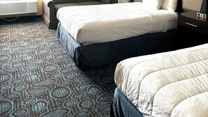 A hotel room with a bed, a chair, a bedside table with a lamp, and a large window with curtains. - Regency Inn and Suites - Handicapped Non Smoking King (New London)