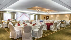 Une salle de banquet avec des tables rondes, des chaises blanches et des lustres.
