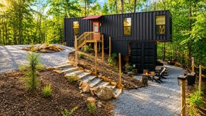 A modern cabin with a red door, a wooden staircase, and a gravel driveway. - Lion Den Cabin A at Walterfalls-Upstate SC (Six Mile)