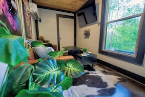 A modern living room with a large window, a flat-screen TV, and a cowhide rug.