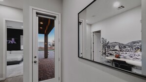 A hotel room with a large mirror reflecting a snowy landscape, a bed, and a bathroom with a shower.