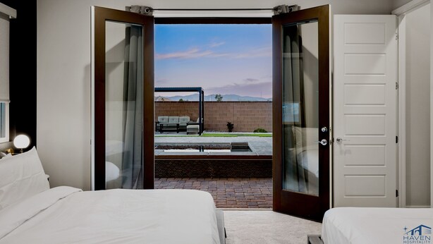 A hotel room with two beds, a view of the outdoors, and a brick wall.