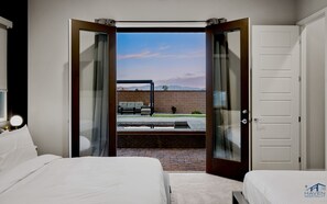 A hotel room with two beds, a view of the outdoors, and a brick wall.