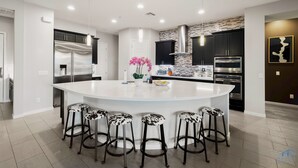 A modern kitchen with a central island, stainless steel appliances, and black cabinetry.