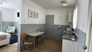 A compact living space with a kitchenette, a dining area, and a bedroom. - Bings Motel (Blenheim)