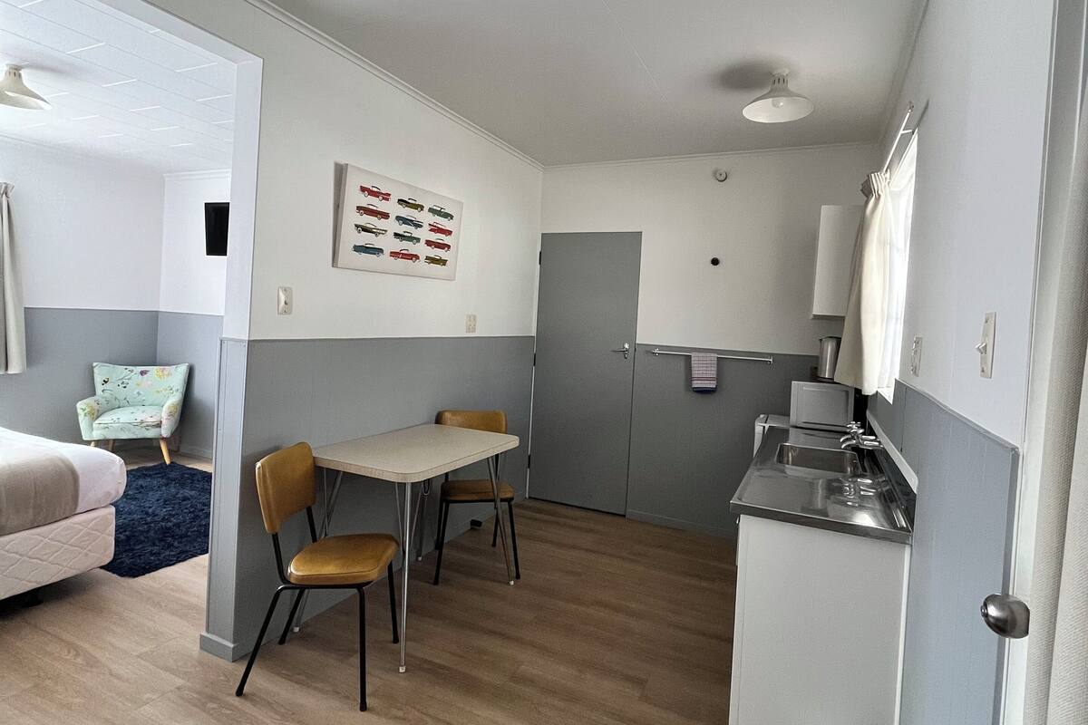 A compact living space with a kitchenette, a dining area, and a bedroom.