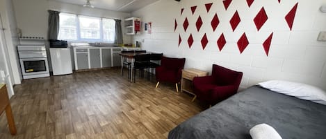 A compact room with a bed, a desk, and a kitchenette.