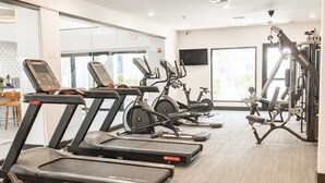 A gym with multiple treadmills, elliptical machines, and weightlifting equipment.