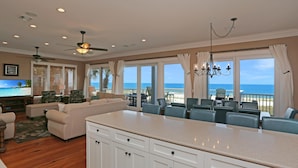 A spacious living area with a large island, a dining area with a view of the ocean, and a ceiling fan. - Moonstruck (Port St. Joe)