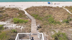 A wooden boardwalk leading to a beach with clear blue water, surrounded by vegetation. - Moonstruck (Port St. Joe)