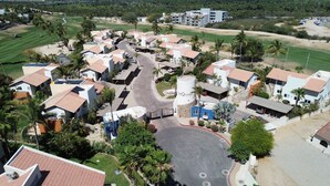 An aerial view of a residential area with houses, a central road, and a large water tank. - Condo. Las Quintas, Terraza, Jardín de Paisaje, Zona de Hoteles, Campo de Golf (San José del Cabo)