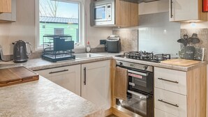 A modern kitchen with a gas stove, oven, microwave, and a window with a view of a green field. - 2 bedroom accommodation in Ashbourne (Ashbourne)