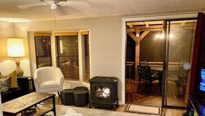 Una sala de estar con sofá, sillón y una mesa con un rompecabezas. Hay una chimenea y un televisor.