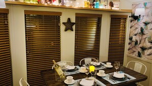 Un comedor con una mesa de madera dispuesta para cuatro personas, con platos, cubiertos y vasos.