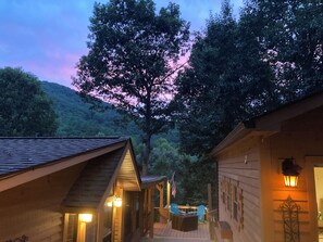 Une cabane dotée d’une terrasse, de murs en bois et offrant une vue sur une colline boisée.