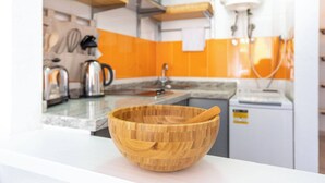Una cocina moderna con un bol de madera sobre la encimera, una cafetera y un hervidor.