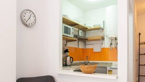 Una cocina moderna con una silla de madera, un lavamanos redondo de madera y un reloj en la pared.