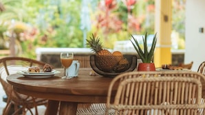A wooden dining table with a bowl of fruit, a glass of juice, and a pitcher. - Kaz Lorizon (Entre-Deux)