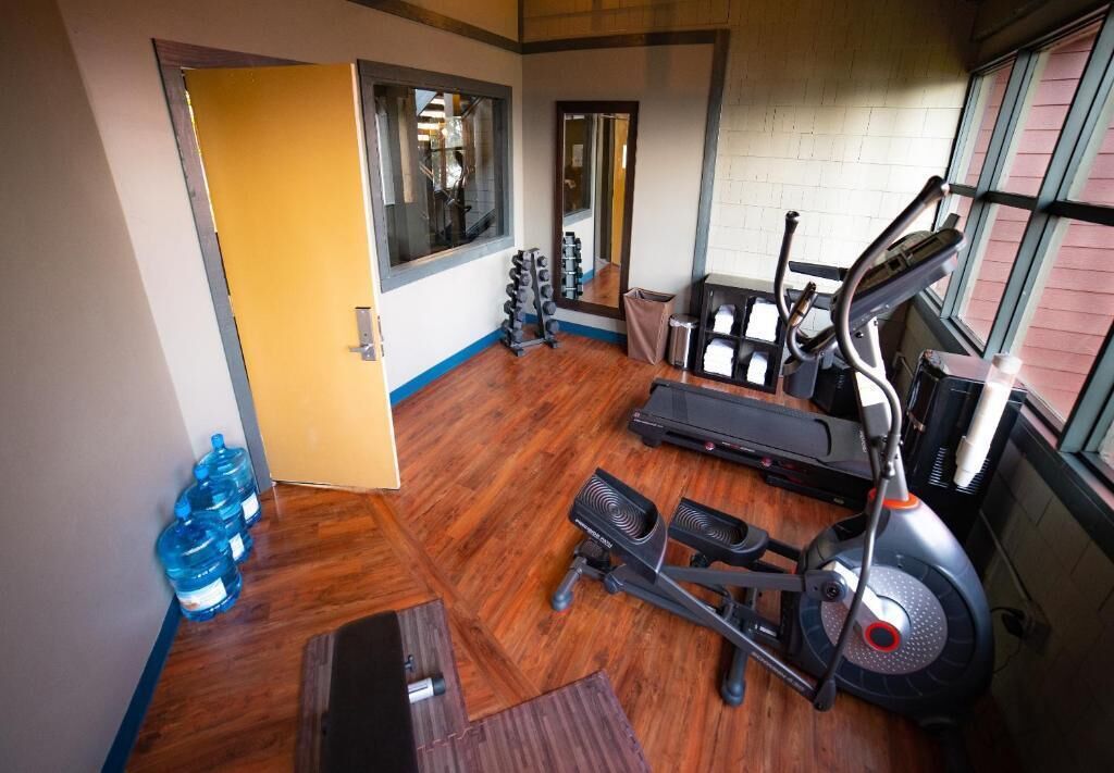 Een fitnessruimte met trainingsapparatuur, een spiegel en waterflessen.