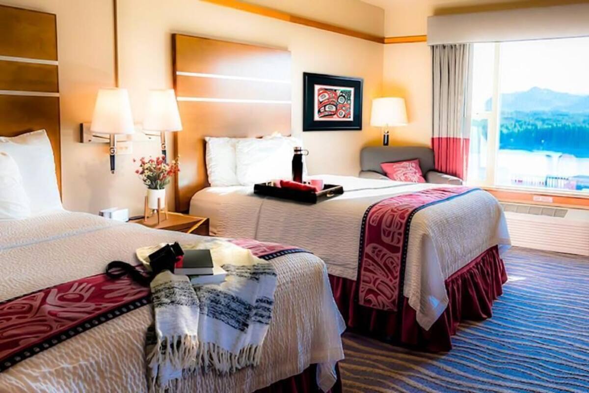 Habitación de hotel con dos camas, un ventanal con vistas a la montaña y una obra de arte enmarcada en la pared.