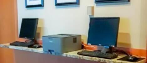 A reception desk with two computers, a printer, and framed artwork on the wall.