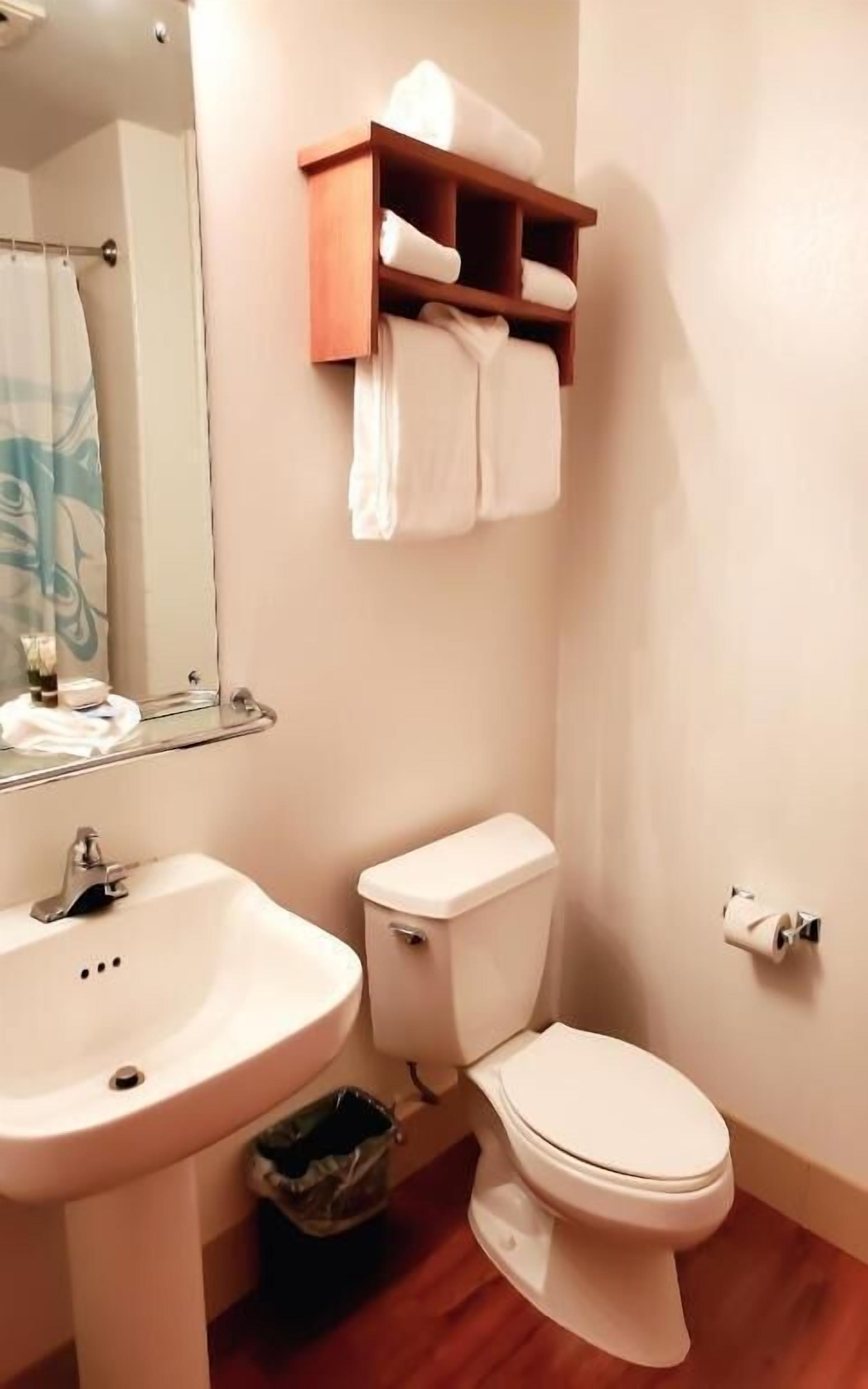 A bathroom with a sink, toilet, and a shelf with towels.